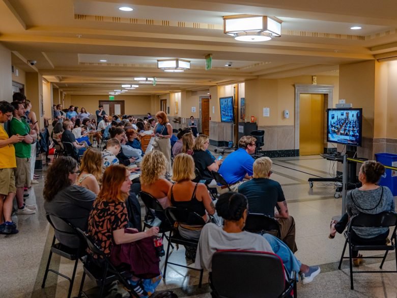 Members of the public watch the Metro Council meeting on data center regulations from an overflow area